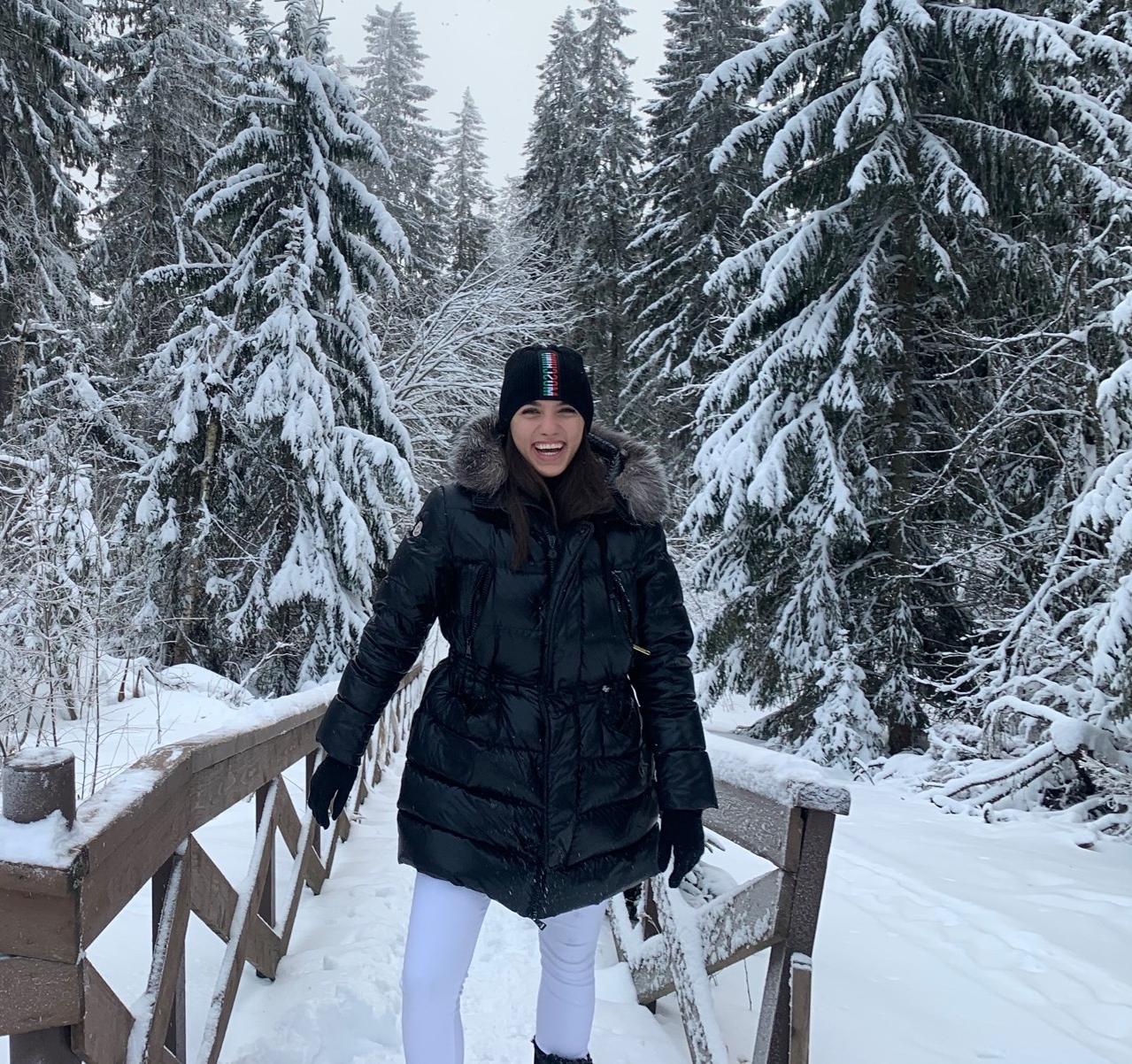 Jelisaveta, smiling and wearing a coat and hat in the snow. 